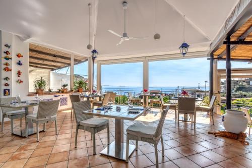 ネラノにあるVillarena Relaisのテーブルと椅子が備わり、海の景色を望むレストラン