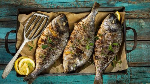 three fish on a tray with a fork and lemon at Kundmalir Gold Coast Beach Resort 