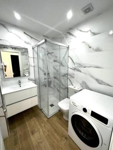 y baño con ducha y lavadora. en Apartamento La Muralla 2D, en Aguilar de Campóo