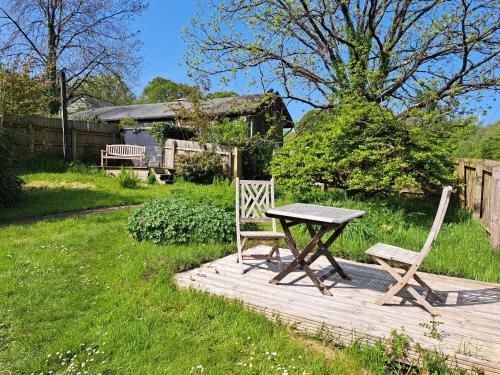 a picnic table and two chairs on a wooden deck at The Holt - a cosy bolthole on a wildlife reserve with hot tub -Exmoor 7m in Oakford