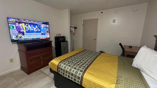 Carom Inn a Travelodge by Wyndham Denham Springs-Baton Rouge في دينهام سبرينغز: غرفة نوم بسرير وتلفزيون بشاشة مسطحة