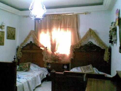 1 Schlafzimmer mit 2 Einzelbetten und einem Fenster in der Unterkunft Laraqui hossini in Fès
