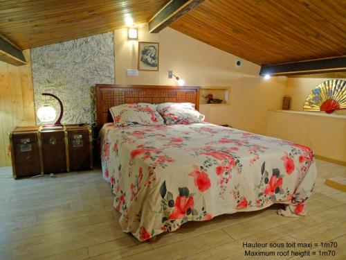 ein Schlafzimmer mit einem Bett mit geblümter Tagesdecke in der Unterkunft La calade de Joux in Chassiers