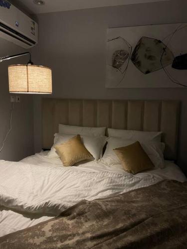 Una cama con sábanas blancas y almohadas en un dormitorio en استديو بتصميم أنيق ودخول ذاتي en Riad