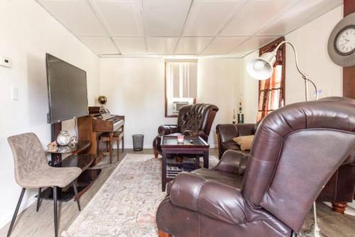een woonkamer met een leren bank en een televisie bij cozy room with private bathroom in Arlington