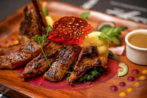 a plate of food with meat and vegetables on a table at Athena Hotel Kampala in Kampala