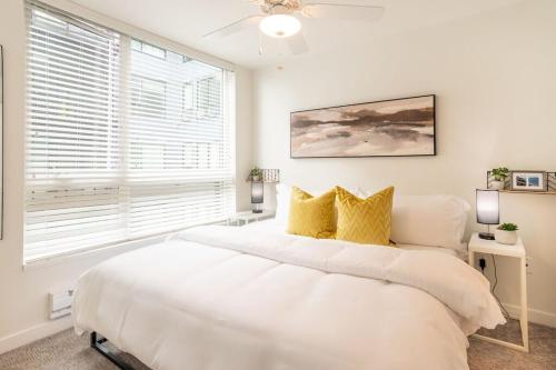1 dormitorio blanco con 1 cama blanca grande con almohadas amarillas en Gymking Bed4k Smart Tvcable360 Rooftop Views, en Tacoma