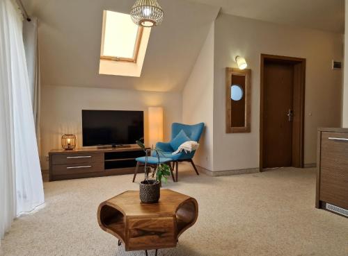 - un salon avec une télévision et une chaise bleue dans l'établissement Hotel 77 Restauracja Spa, à Chałupy