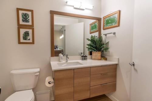 La salle de bains est pourvue d'un lavabo, de toilettes et d'un miroir. dans l'établissement Palm Theme King Bed Paid Garage 55" 4k Smart T, à Tacoma