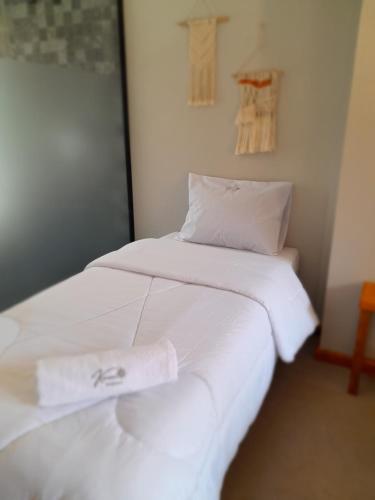 two beds in a room with white sheets and towels at Pousada Kirana in Praia do Rosa