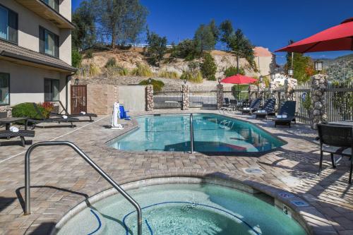 una piscina en un patio con sillas y un edificio en Yosemite Southgate Hotel & Suites, en Oakhurst