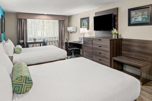 a hotel room with two beds and a desk at Yosemite Southgate Hotel & Suites in Oakhurst