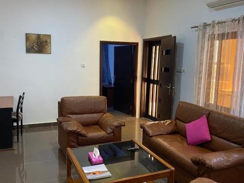 a living room with two leather couches and a table at Cozy Apartment in Cotonou