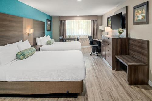 a hotel room with two beds and a desk at Yosemite Southgate Hotel & Suites in Oakhurst