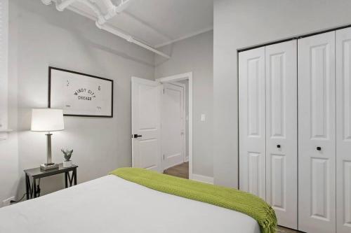 a white bedroom with a bed with a green blanket at Cozy Chic 1BR Chicago Apartment - Hartrey G in Evanston