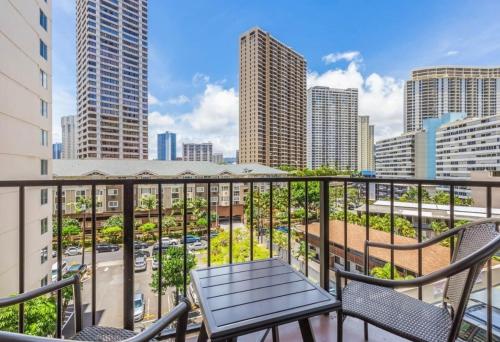 a balcony with chairs and a view of the city at Spacious & Sophisticated Palms Studio condo in Honolulu