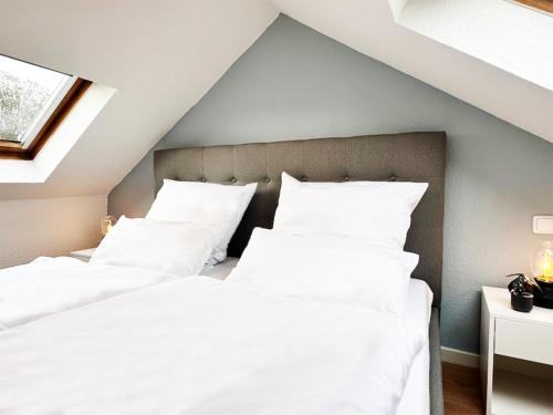 2 bedden in een zolderslaapkamer met witte kussens bij Modernes City-Apartment in Mönchengladbach in Mönchengladbach