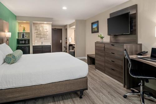 a hotel room with a bed and a desk and a computer at Yosemite Southgate Hotel & Suites in Oakhurst