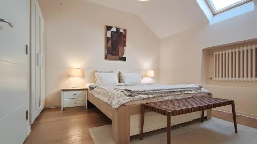 a bedroom with a bed with a bench in it at FilinHome Papa Suite 2 in Novi Sad