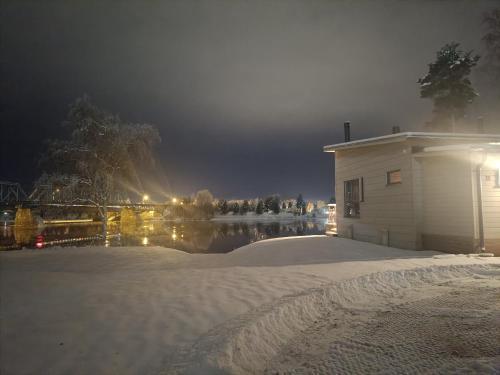 un edificio nella neve vicino a un lago di notte di Villa Riverside a Rovaniemi