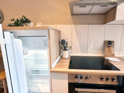 Il comprend une cuisine équipée d'une cuisinière. - un four à côté d'un réfrigérateur ouvert dans l'établissement Modernes City-Apartment in Möchengladbach, à Mönchengladbach
