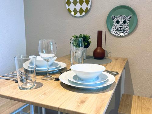 een houten tafel met borden en wijnglazen erop bij Modernes City-Apartment in Möchengladbach in Mönchengladbach