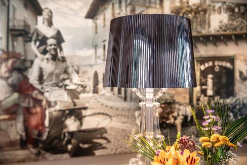 Boutique-HOTEL REMORINO, a Private Selection Hotel في لوكارنو: طاولة مع مصباح وورود أمام لوحة