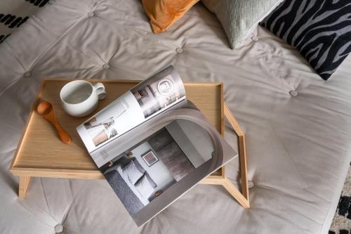 a tray with a book and a cup on a bed at Viihtyisä yksiö, oma parkkipaikka, wifi, Aino Areena 300m in Järvenpää