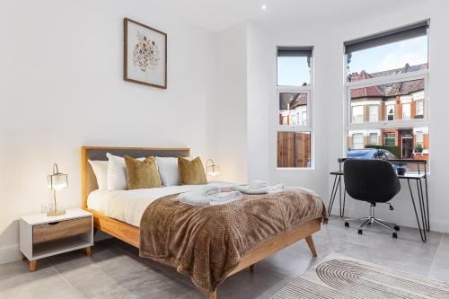 a bedroom with a bed and a desk and two windows at SERCASA - Woodside Park - North Finchley in Whetstone