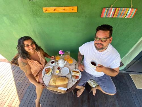 a man and a woman sitting at a table with food at Casa Raízes Capão in Vale do Capao