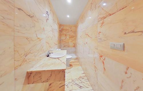 a marble bathroom with a toilet and a sink at LOS MIRLOS in Navaluenga