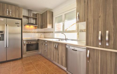 a kitchen with wooden cabinets and stainless steel appliances at LOS MIRLOS in Navaluenga