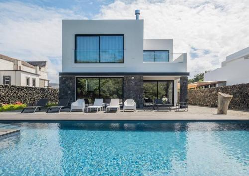 a house with a swimming pool in front of a house at Lotus House - Heated Pool & Jacuzzi near the Beach in Ponta Delgada
