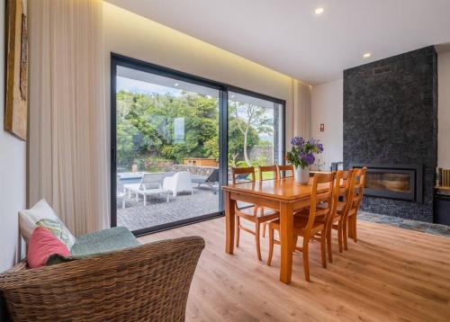 a dining room with a table and chairs and a fireplace at Lotus House - Heated Pool & Jacuzzi near the Beach in Ponta Delgada