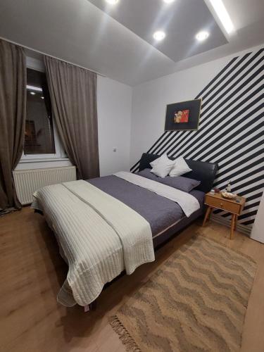 a bedroom with a bed with a striped wall at The SKVER-Elegant City Apartmant in Požarevac