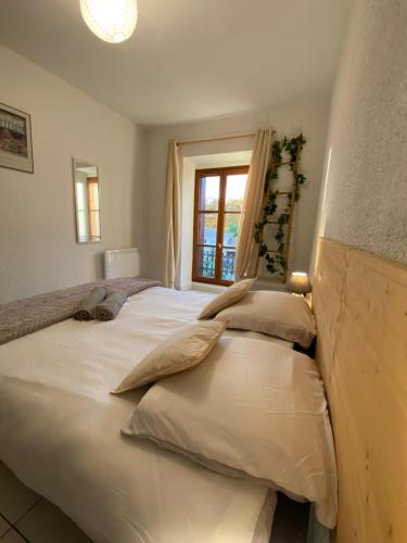 een slaapkamer met een groot wit bed en een raam bij Au pied de la cité, T3 au calme in Carcassonne