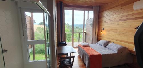 ein Schlafzimmer mit einem Bett und einem großen Fenster in der Unterkunft Pousada Bracatinga in Bom Retiro