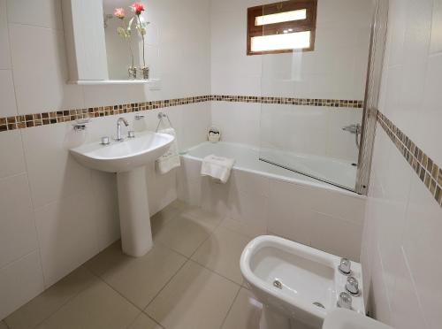 a white bathroom with a sink and a bath tub at Villa Escondida in El Hoyo