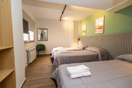 een kamer met drie bedden en handdoeken erop bij M383 Hotel Bariloche in Bariloche