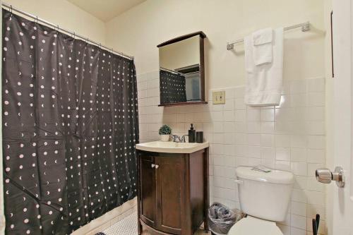 a bathroom with a shower curtain and a toilet at Cozy and Inviting Two-Bedroom Apartment - Sunnyside 3F in Chicago