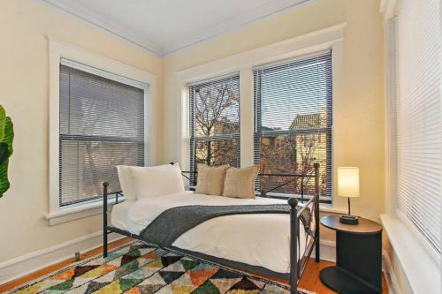 a bedroom with a bed and two windows at Cozy and Inviting Two-Bedroom Apartment - Sunnyside 3F in Chicago