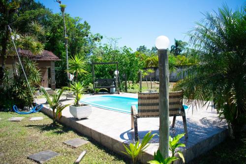 une chaise assise à côté de la piscine dans l'établissement Casa a 5 min do Balneario Coroados - Guaratuba PR, à Guaratuba