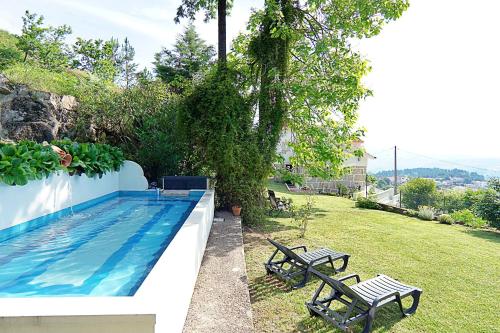 a backyard with a swimming pool and two benches at Casa dos Plátanos near the center of Amarante, Golf Course and Water Park. in Amarante