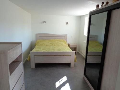 1 dormitorio con cama amarilla y espejo en Appartement indépendant dans villa accessible PMR, en Saint-Chamond