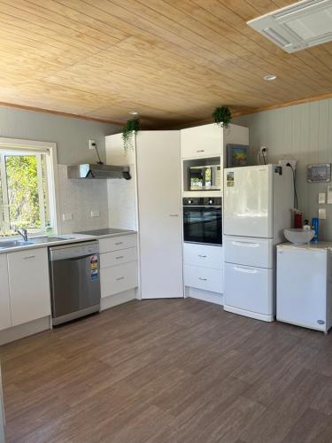 a kitchen with white appliances and a wooden ceiling at Graydon Grove in Kaiteriteri