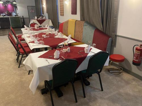 a row of tables in a restaurant with red chairs at The Ivy in Lincolnshire