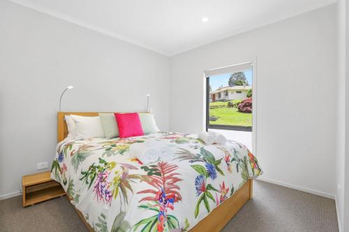 a bedroom with a bed with a floral bedspread and a window at All Good in Rotorua