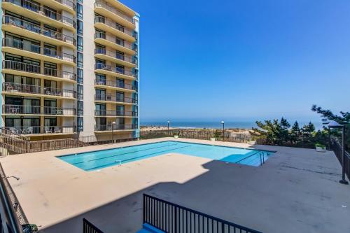 a swimming pool in front of a building with the ocean at Braemar Towers in Ocean City