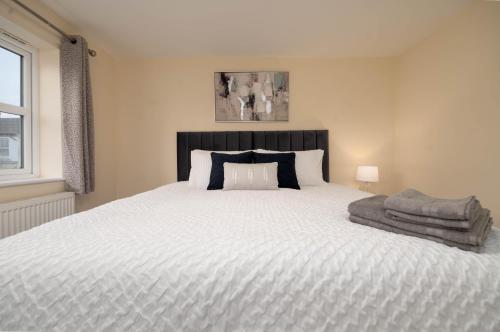 um quarto com uma grande cama branca e uma cabeceira preta em Stunning 3 bed with parking & garden em Market Rasen