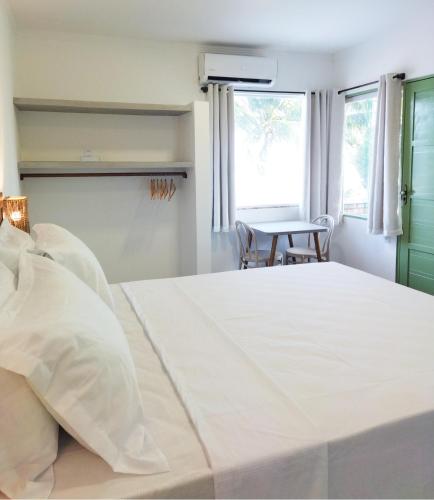 a bedroom with a large white bed and a table at Pousada Fenícia in Japaratinga